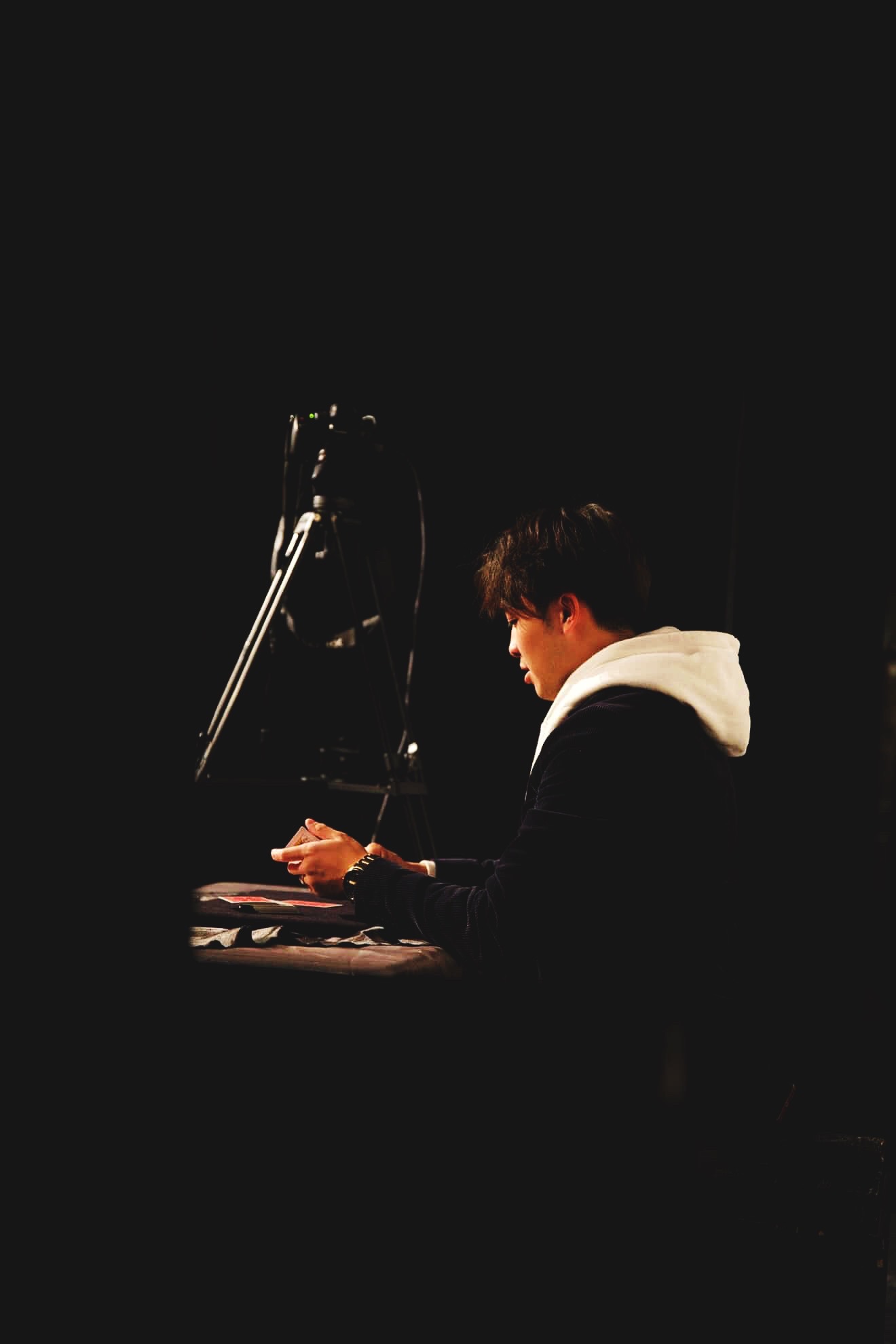 Jason Wong performing card magic at a table under a spotlight